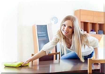 Woman ironing a cloth to hide scratches on wood.