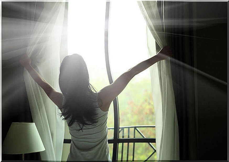 Woman letting natural light into the room.