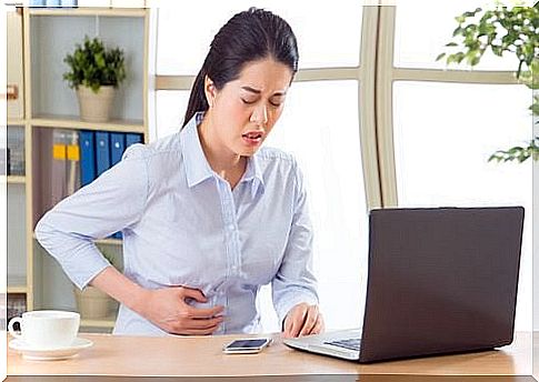 Woman at the computer with a stomachache.