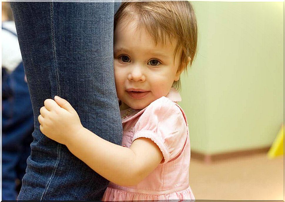 child clinging to mother's leg