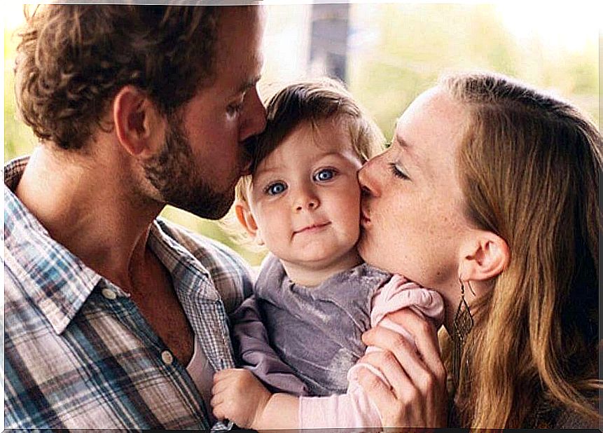 parents kissing their little daughter