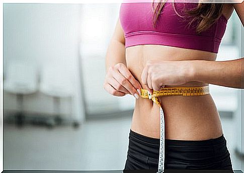 Woman measuring waist with measuring tape.