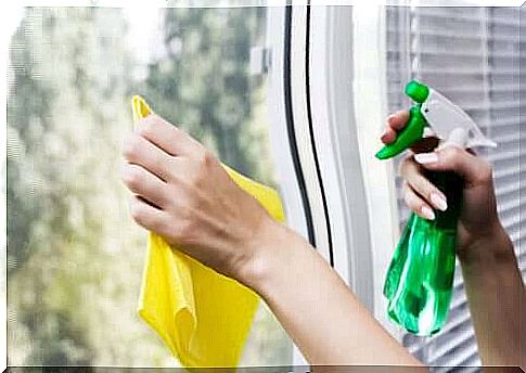 Hands cleaning the glass with a spray and a cloth